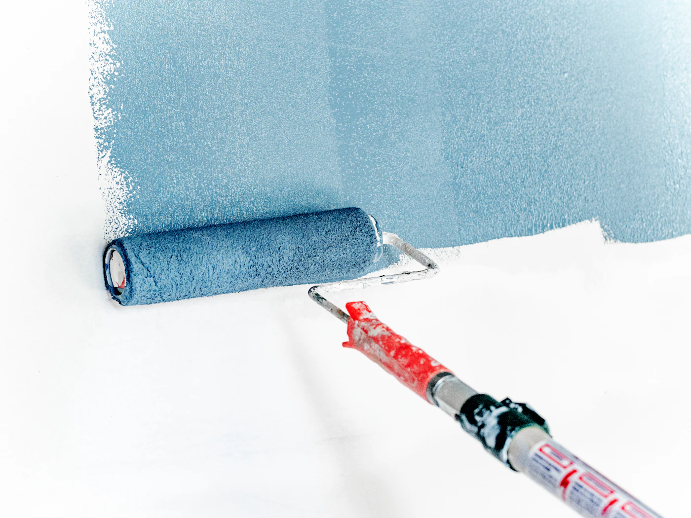 Rolo a aplicar tinta azul numa parede branca